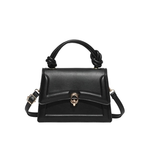 Minimalist black trapezoid handbag with knotted handle and golden ring buckle
