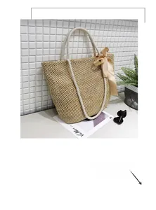 Detail of woven straw tote bag with white rope handles and a cream satin bow accent