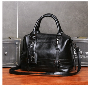 Detail of black pebbled leather Boston bag with metal buckle and detachable shoulder strap
