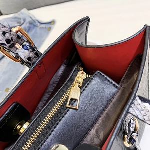Detail of red lining, black zipper pocket, and snakeskin handle with gold buckle