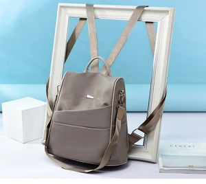 Close-up of coffee brown nylon backpack with silver hardware and multiple zipper pockets