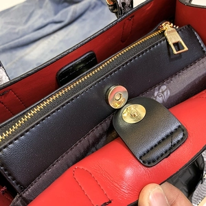 Detail of red faux crocodile skin handbag showing magnetic snap closure and golden hardware