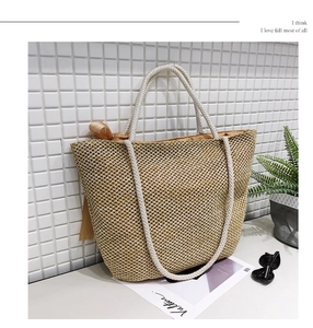 Close-up of large straw tote bag with white rope handles and brown silk bow detail