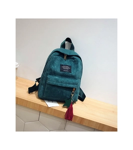 Detail of teal corduroy backpack featuring front zipper pocket and decorative tassel charm