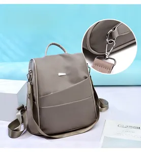 Detail of greyish-khaki oxford backpack showing metal hardware and detachable strap