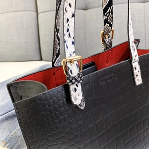 Close-up of black crocodile pattern tote bag with red lining and snake skin strap detail