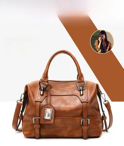 Detail of retro brown lychee textured Boston handbag with dual handles and metal tag