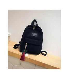 Close-up of black corduroy mini backpack with tassel zipper and embroidered travel patch