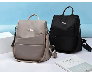 Detailed view of fashionable Oxford fabric backpacks in taupe and black with silver hardware