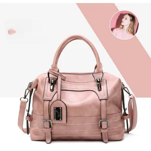 Close-up of pink Boston handbag with leather texture, dual handles and metal buckles