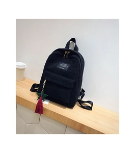 Detail of black corduroy backpack with front zipper pocket and decorative tassel ornament