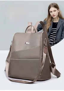 Detail shot of khaki Oxford fabric backpack featuring premium metallic logo plate