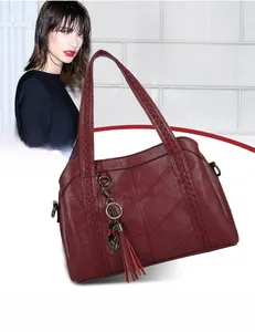 Détail du sac cabas bordeaux avec pompon, poignée tressée et clous de fond en métal