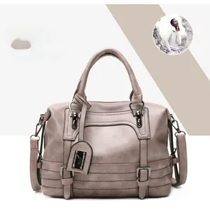 Detail view of a gray vintage cross-body bag featuring decorative straps and metal hardware