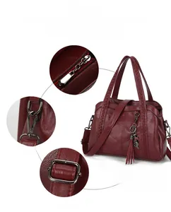 Détails du sac à main bordeaux à motif litchi avec pendentif pompon et ferrures métalliques