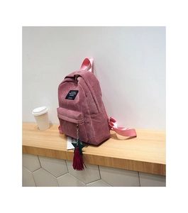 Detailed close-up of pink corduroy backpack with living traveling share woven label