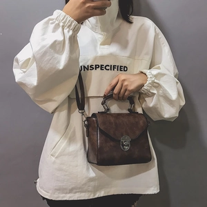 Dettaglio borsa in pelle marrone scuro con manico metallico e chiusura a girello vintage