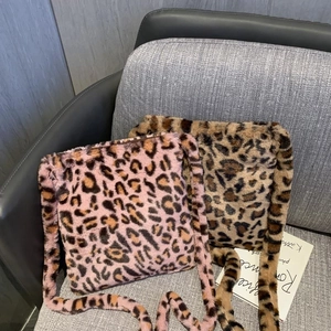 Sacs bandoulière en peluche léopard rose et marron posés sur un canapé gris