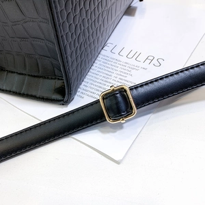 Macro detail of black crocodile pattern leather texture and golden adjustable buckle