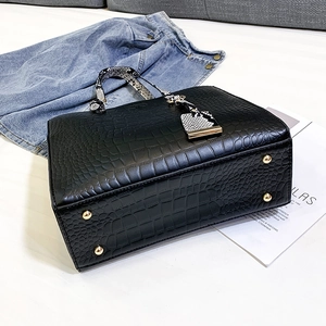 Detailed macro view of black crocodile pattern leather handbag with metal base studs