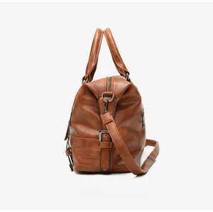 Detailed side view of brown leather Boston bag with metallic buckles and shoulder strap