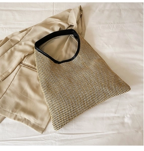 Detail of woven straw tote bag with black leather handles and trim for summer beach style