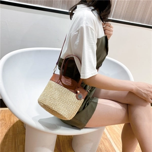 Borsa a secchiello in paglia con finiture in pelle marrone indossata da una modella