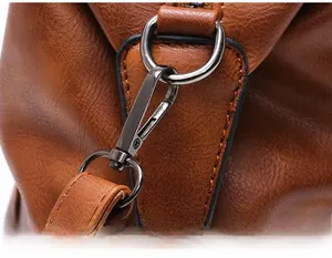 Detailed close-up of gunmetal hardware connector on brown lychee pattern leather handbag