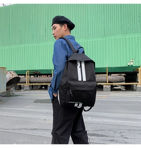 Detail of black nylon backpack with vertical white stripes and front zipper pocket