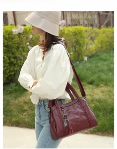 Gros plan du sac cabas bordeaux en cuir texturé avec poignée tressée et charm chat