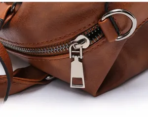 Close-up of smooth silver zipper and durable D-ring hardware on brown faux leather bag