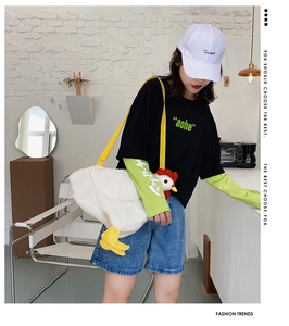 Detail of soft white plush chicken shoulder bag with yellow strap on a casual model