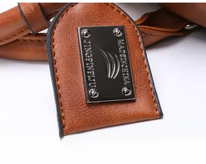 Close-up of silver metal logo plate on brown lychee texture faux leather handbag