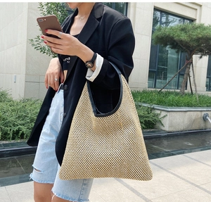Detail of woven straw shoulder bag with black leather handles and trim for summer beach