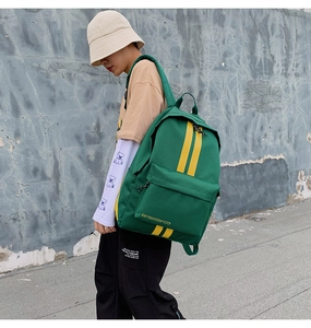 Detail view of green canvas backpack with vibrant yellow stripes in trendy urban style