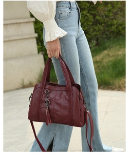 Détail du sac cabas bordeaux en cuir texturé avec pompon et poignées tressées