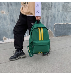 Detail of dark green canvas backpack featuring vibrant yellow contrast vertical stripes