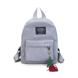 Macro view of blue corduroy backpack featuring front zipper pocket and star tassel charm