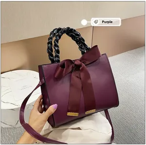 Détail du sac à main violet en cuir PU avec nœud bordeaux et poignée tressée noire