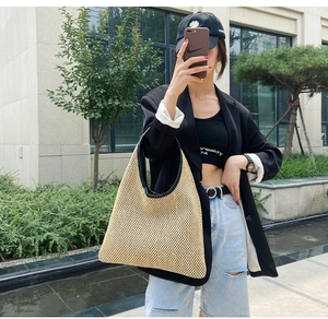 Detail view of straw beach tote featuring natural woven texture and black handle accents