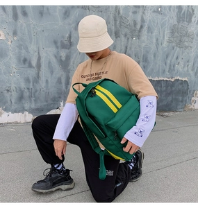 Detail of forest green canvas backpack with yellow stripes in a street style setting