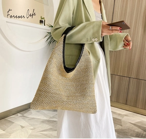 Spacious woven beach tote bag with black leather trim worn by model in a cafe setting