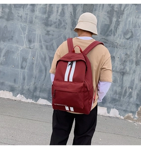 Detail of burgundy canvas backpack featuring white stripes and comfortable wide straps