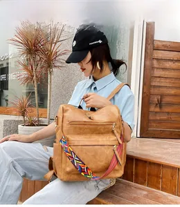 Détail d'un sac à dos en similicuir marron avec bandoulière tissée de style ethnique