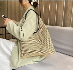 Detail view of large straw tote bag with black leather straps and trim for summer style