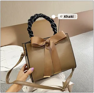 Détail du sac en cuir kaki avec un grand nœud en ruban et une poignée tressée noire