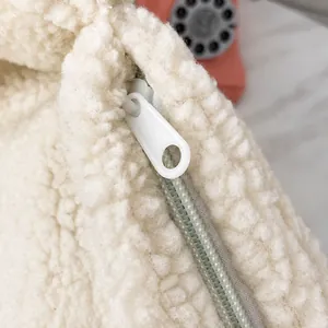 Close-up of smooth white plush fabric with a high-quality zipper and round pull tab