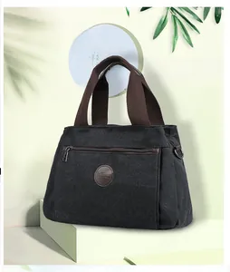 Detailed close-up of dark grey canvas travel bag featuring brown straps and leather logo