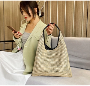 Detail of hand-woven straw hobo bag featuring contrast black leather trim and wide handle