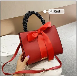 Vue détaillée du sac à main en cuir rouge avec poignée tressée noire et nœud en satin